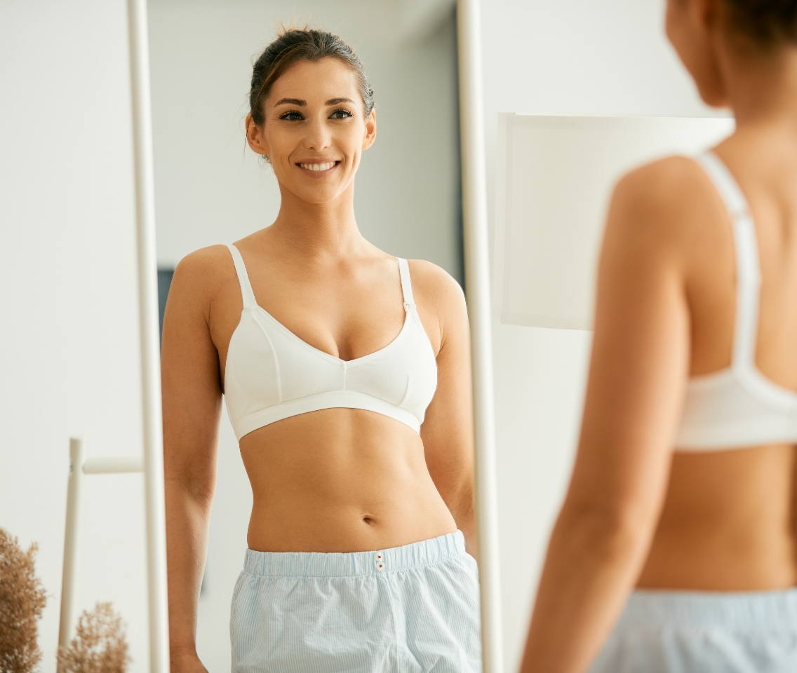 Brunette woman in athletic bra smiling in mirror