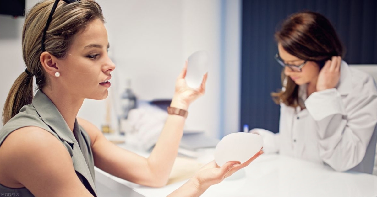 Plastic surgery consultation with a model comparing breast implant options. (models)