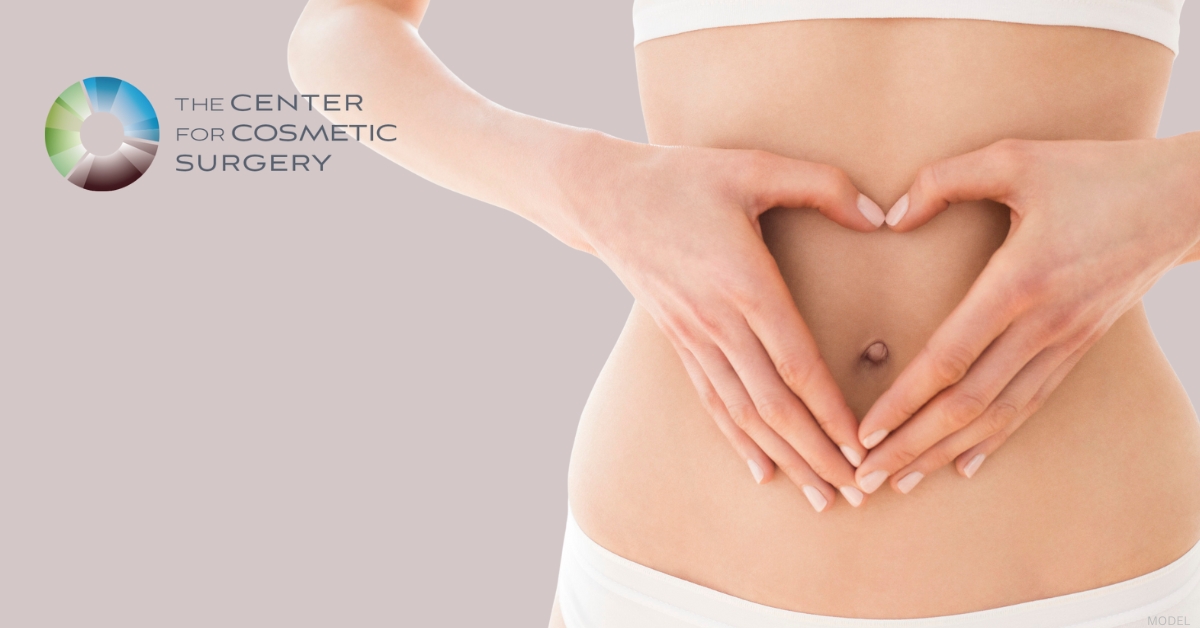Torso model illustrating mommy makeover preparation, with hands forming a heart shape over the abdomen. (model)