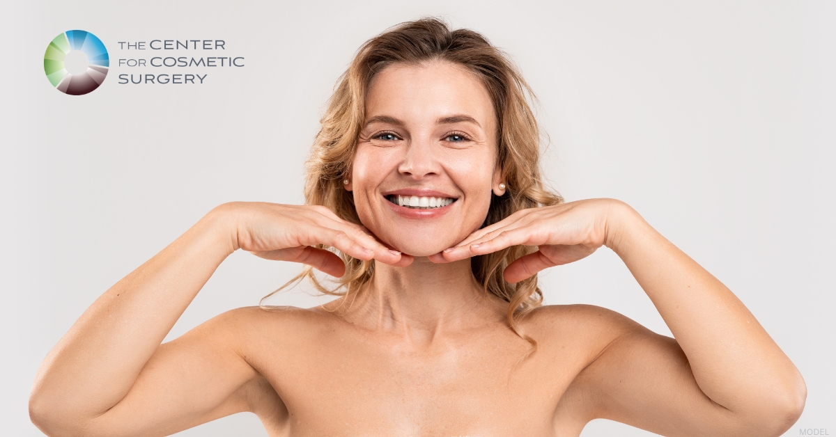 Woman smiles while holding her hands to their face. (model)