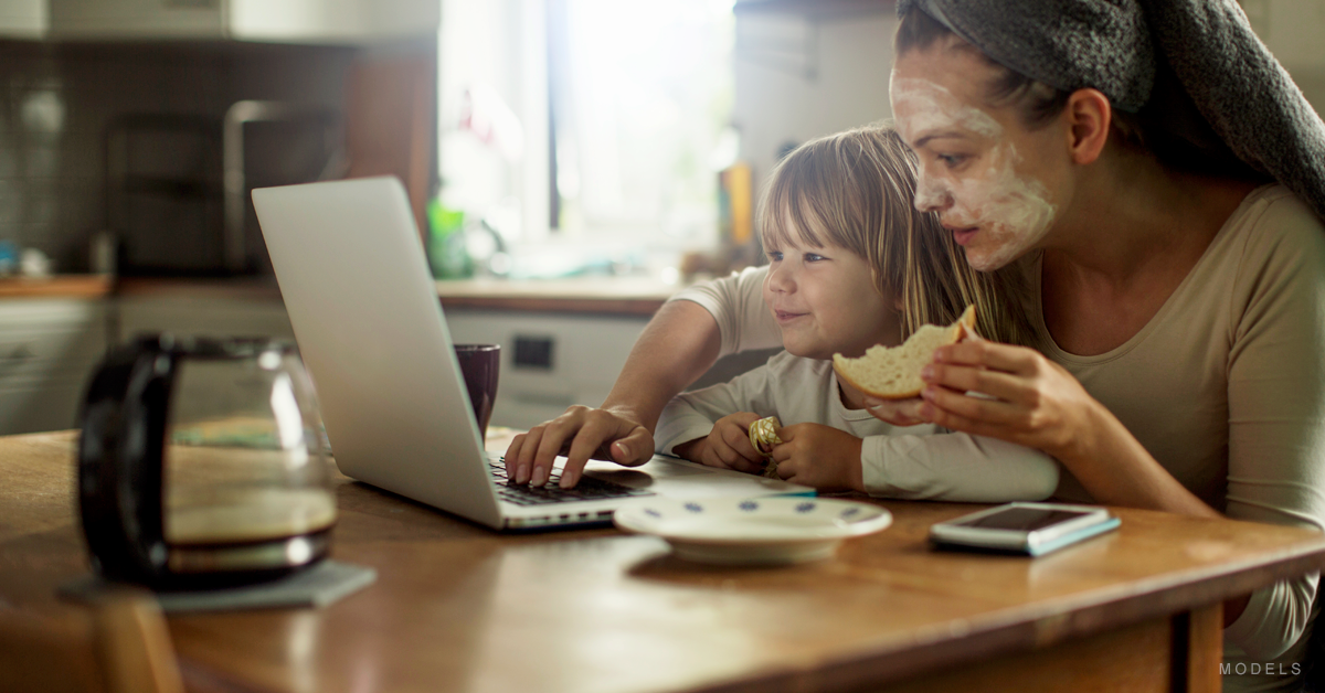 A mother and her child browse the web while eating a snack.