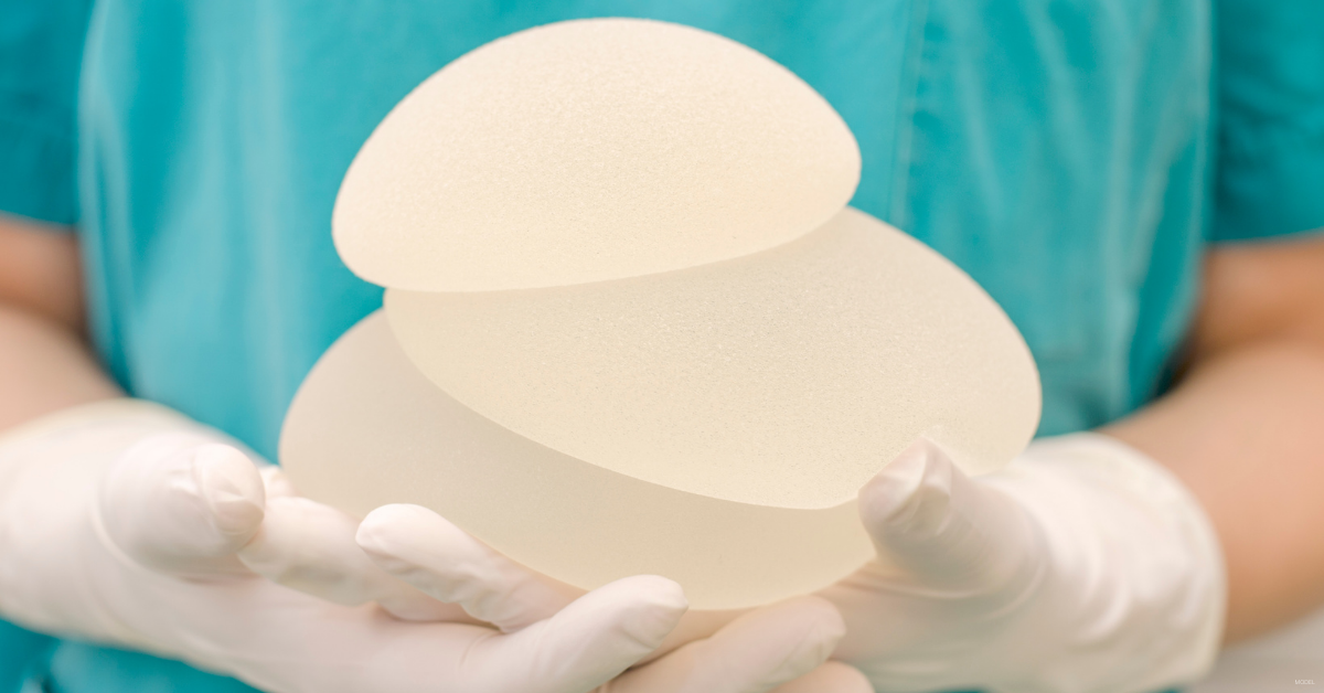 A doctor holds breast implants. 