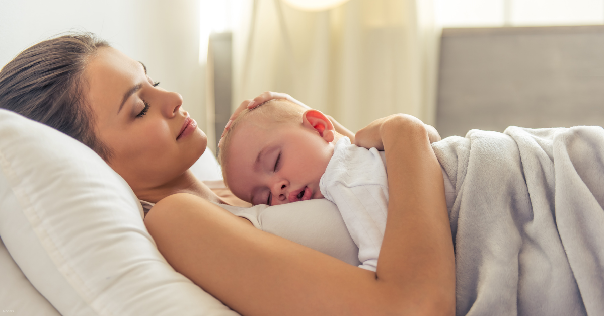 A woman rests with her new born baby.