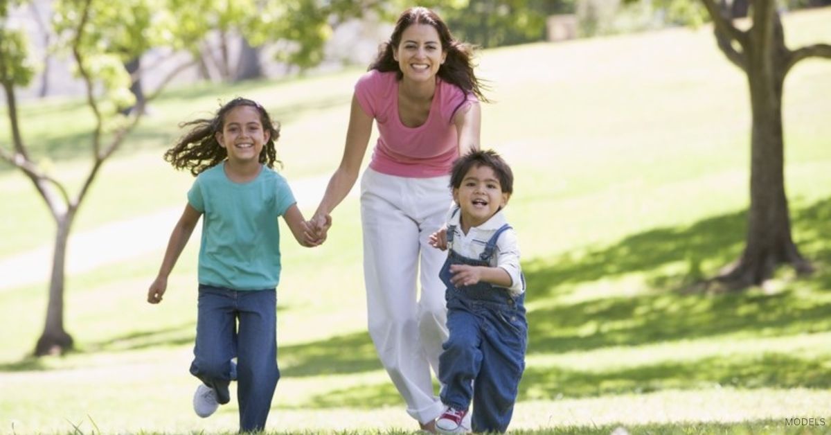 Mom running with her two children (MODELS) through a field.