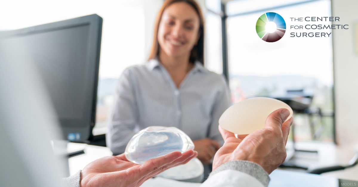 Surgeon showing two breast implants to a patient interested in a breast augmentation (models)